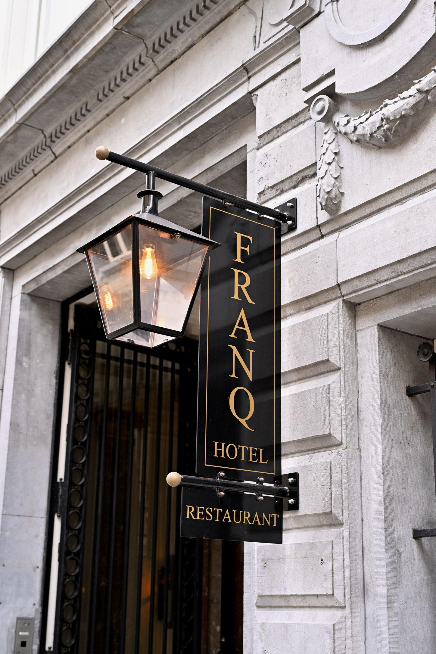 Hotel FRANQ Restaurant sign and lantern on the pale Kipdorp façade