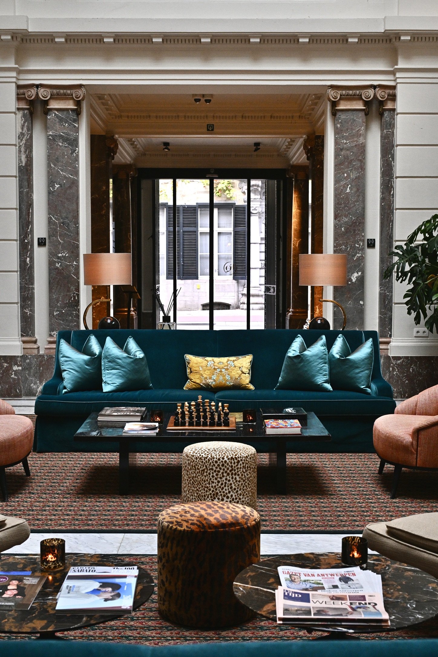 Hotel FRANQ lounge with a teal sofa, marble columns, chessboard and leopard-patterned stools