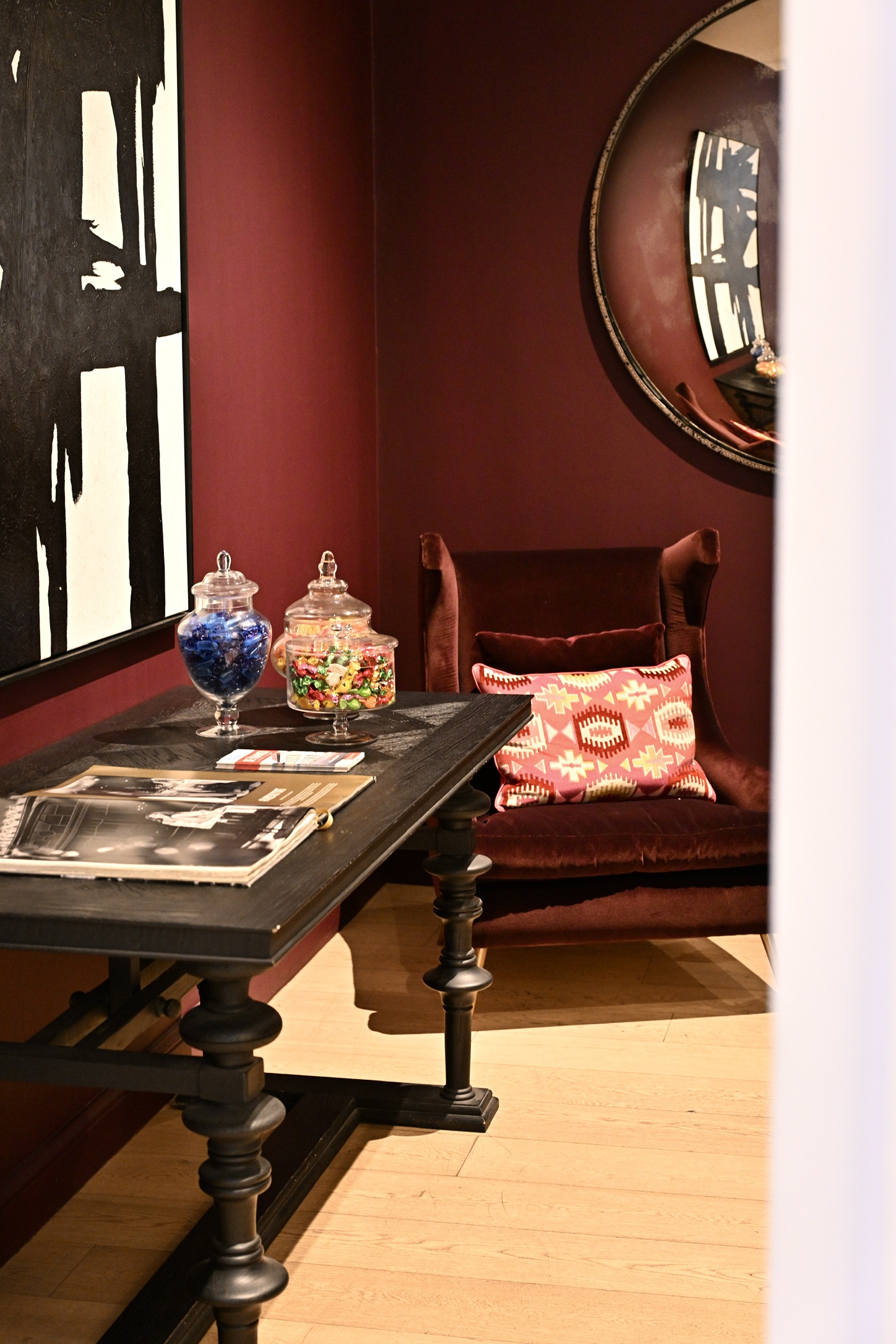 Hotel FRANQ’s small lounge with a burgundy armchair, books, sweet jars and mirror